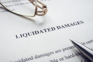 Documents about Liquidated damages with a pen and glasses.