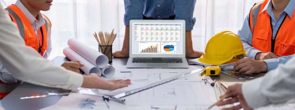 Table with a hard hat, tape measurer, blueprints, and financial statements.
