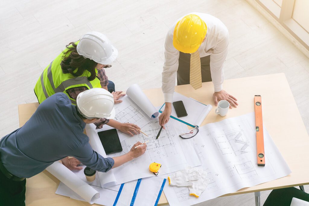 Construction contractor and team reviewing blueprints together, representing business transition planning and key employee succession strategies for California construction companies